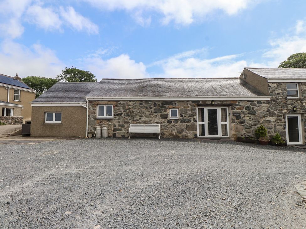 An outdoor area with a stone building and a bench at Coetsiws in Clynnog Fawr