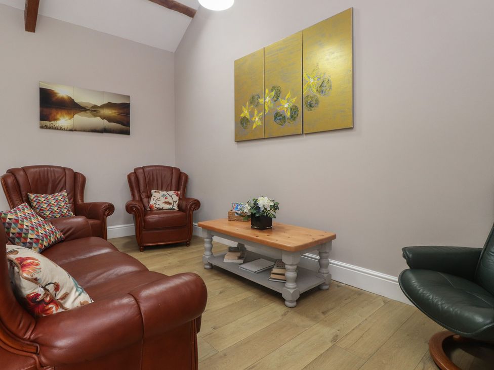 A living room with leather chairs and a coffee table at Coetsiws in Clynnog Fawr