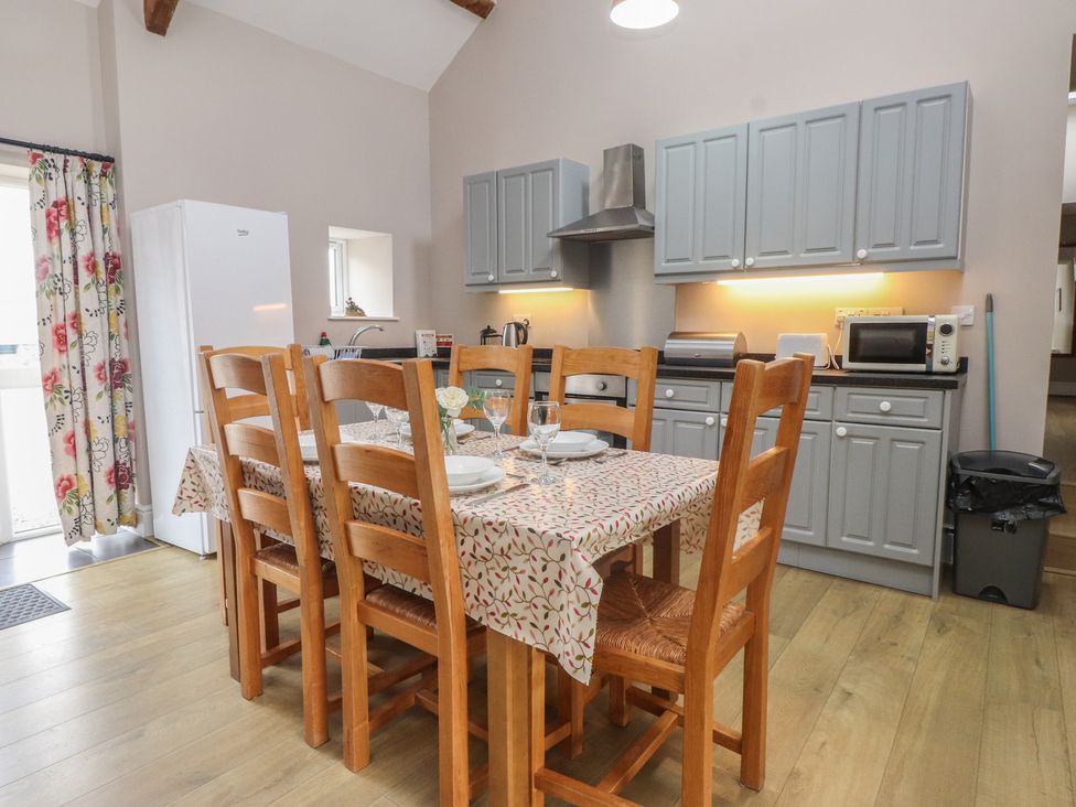 A kitchen with dining table and appliances at Coetsiws in Clynnog Fawr