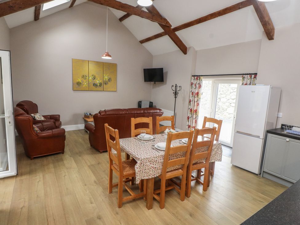 A living room with dining table and seating area at Coetsiws in Clynnog Fawr