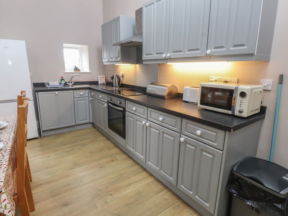 A kitchen with cupboards and appliances at Coetsiws in Clynnog Fawr