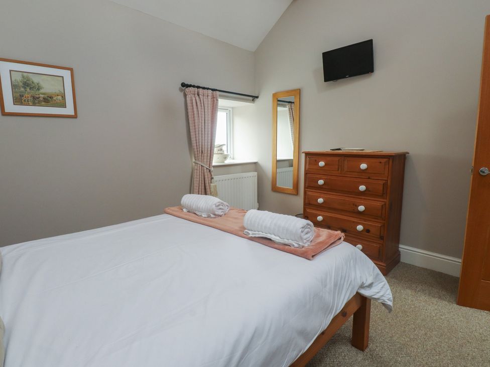 A bedroom with a bed and dresser at Coetsiws in Clynnog Fawr