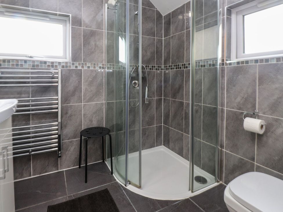 A bathroom with a shower and towel radiator at Coetsiws in Clynnog Fawr