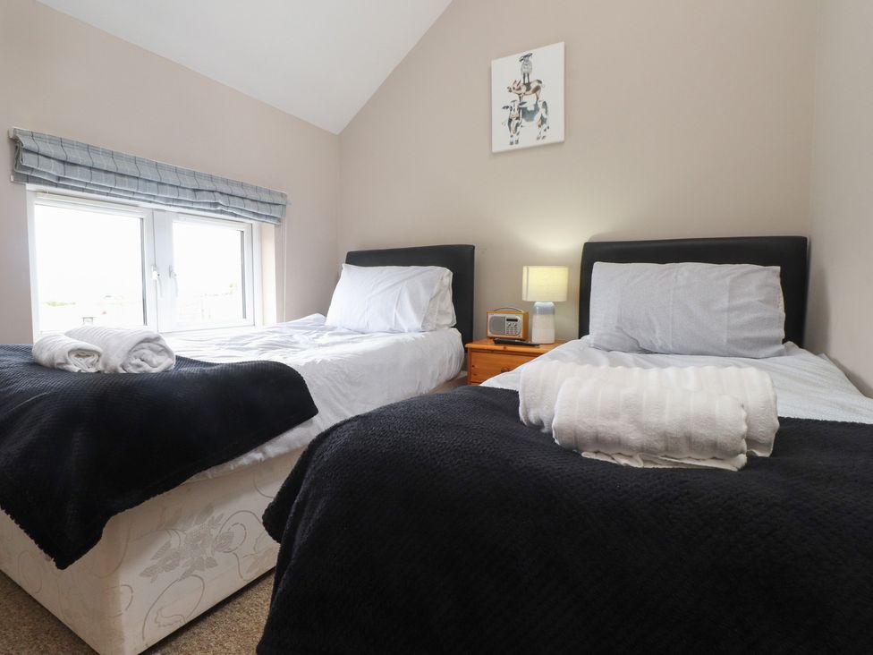A bedroom with two beds and a bedside table at Coetsiws in Clynnog Fawr