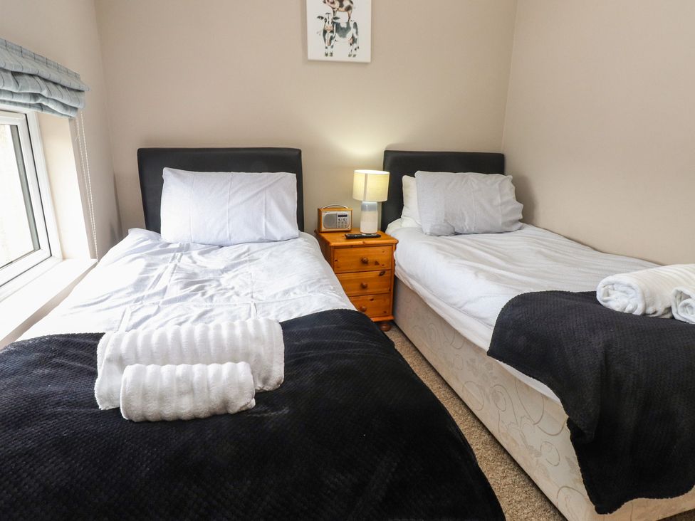 A bedroom with two single beds and a nightstand at Coetsiws in Clynnog Fawr
