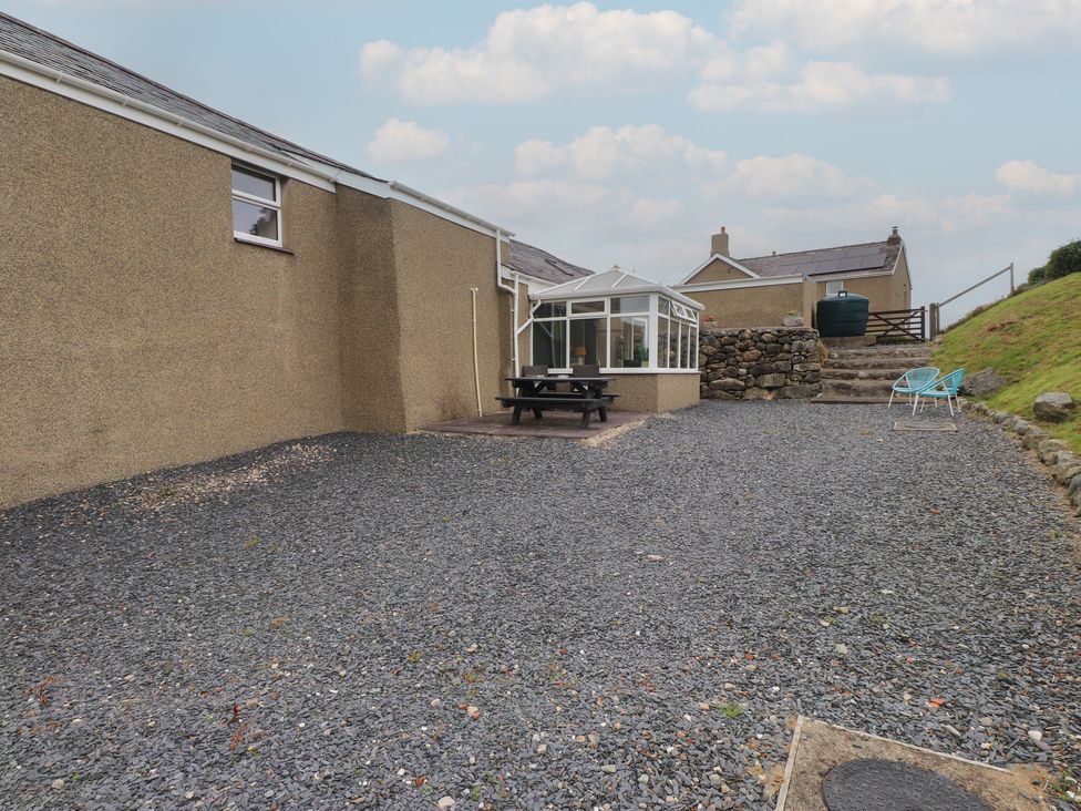 A garden area with a conservatory and dining table at Coetsiws in Clynnog Fawr
