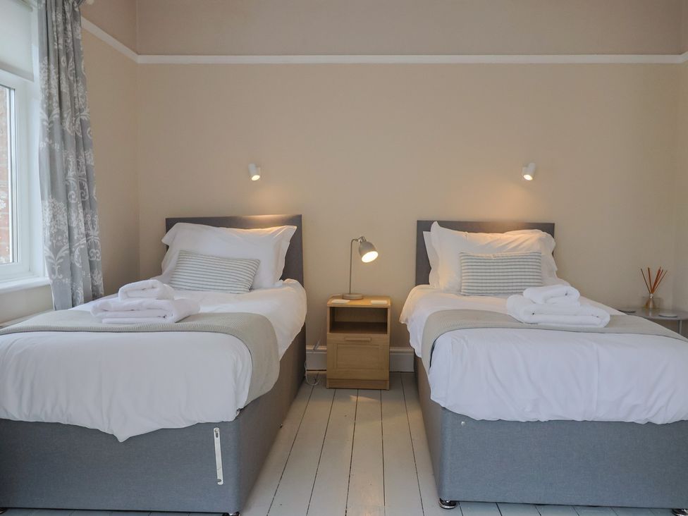 A bedroom with two beds and a lamp on a nightstand at Sunny Croft in Broadmayne near Dorchester