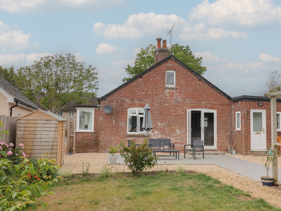 A garden with a brick house and patio seating at Sunny Croft in Broadmayne near Dorchester