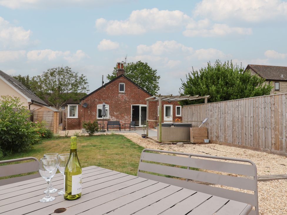 A garden with a table, chairs and hot tub at Sunny Croft in Broadmayne near Dorchester