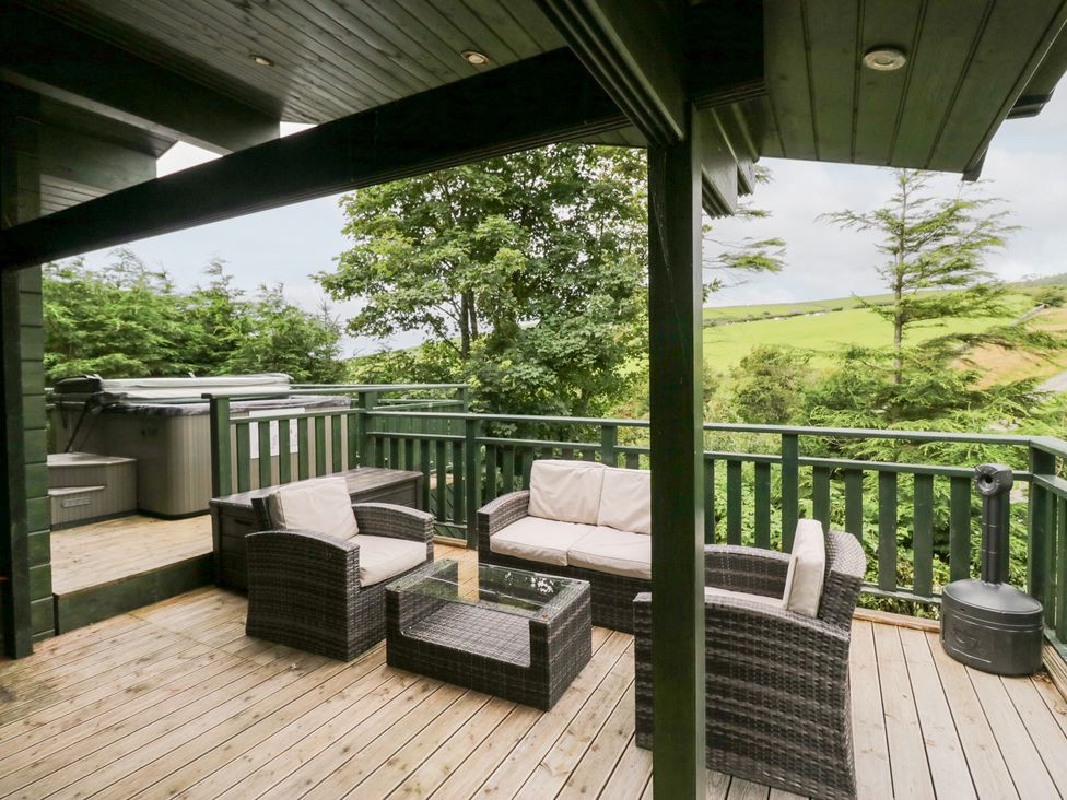 A deck with outdoor furniture and a hot tub at Oak Lodge in Pennington near Ulverston