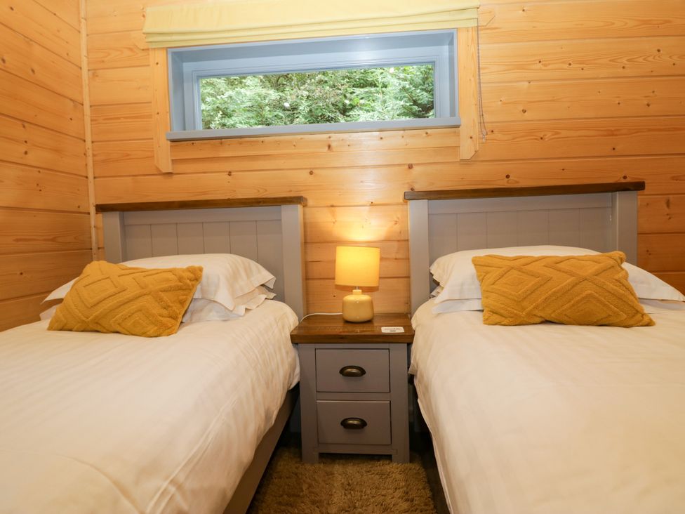 A bedroom with two beds and a lamp in Oak Lodge Pennington near Ulverston