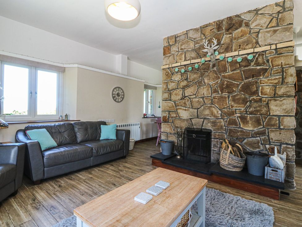 A living room with a stone wall and sofa at Tyn Morfa in Llangwnnadl near Aberdaron