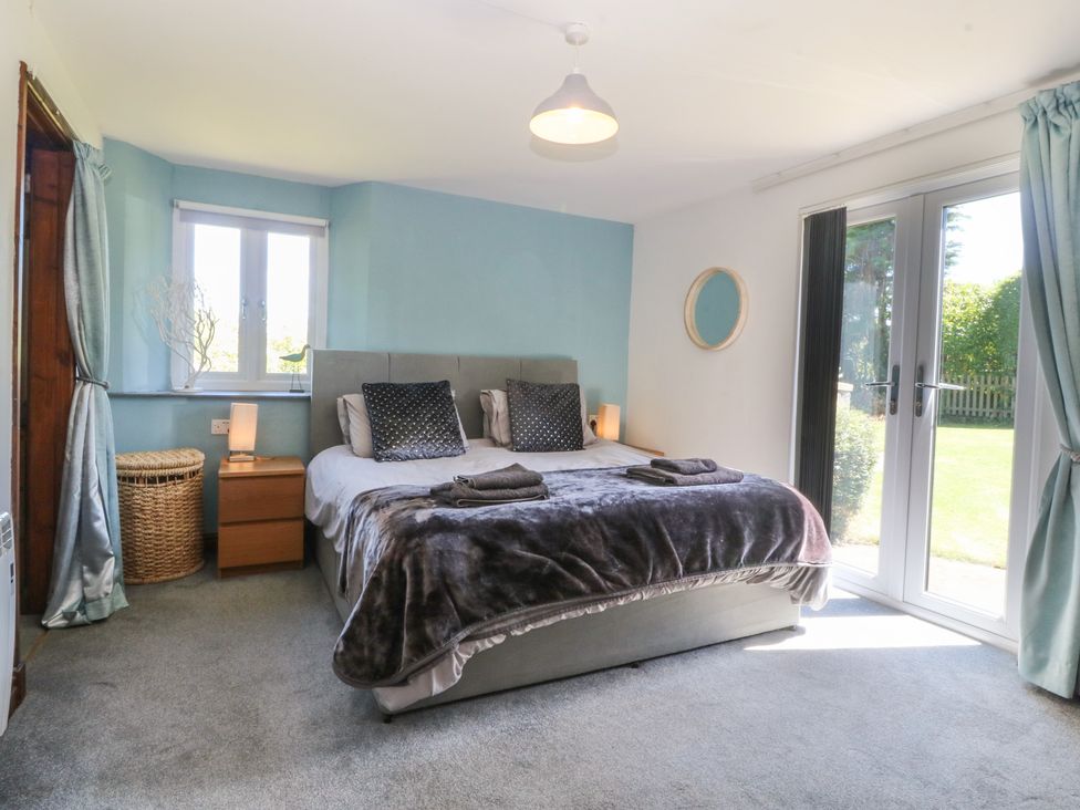 A bedroom with a bed and sliding doors at Tyn Morfa in Llangwnnadl near Aberdaron