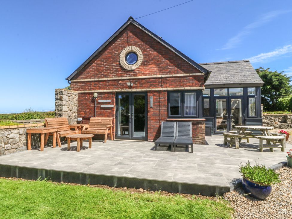 A house with patio furniture and a stone wall at Tyn Morfa in Llangwnnadl near Aberdaron