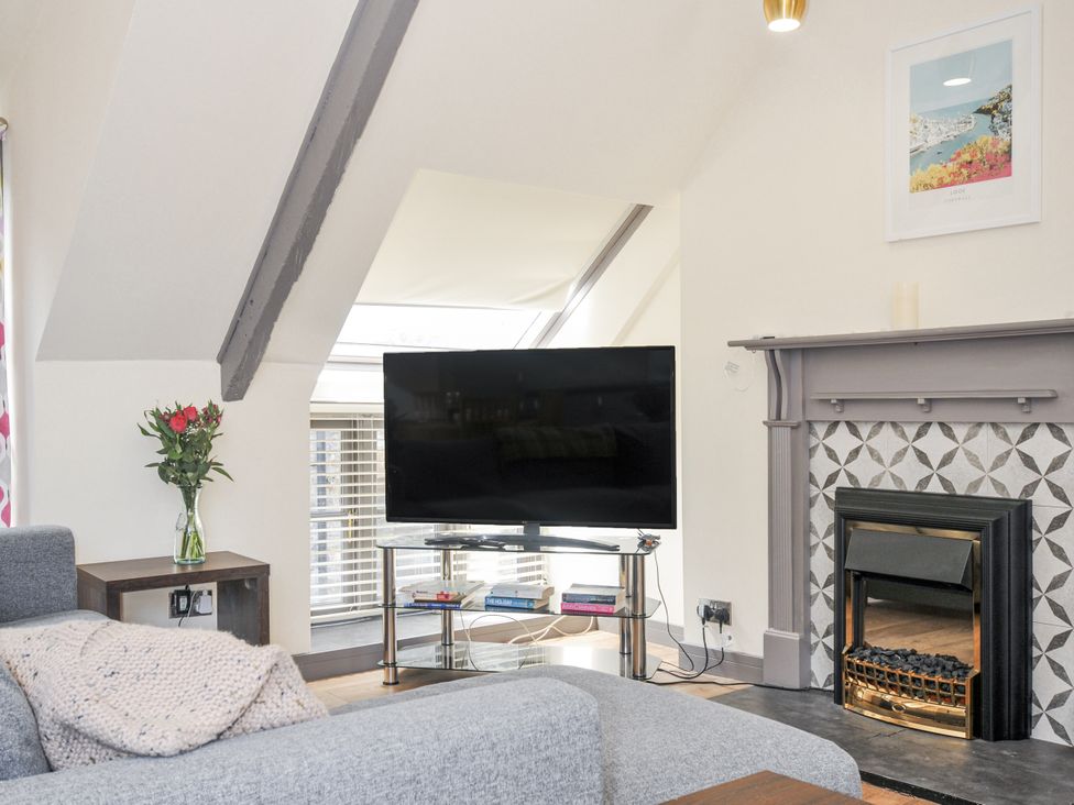 A living room with a television and sofa at Beach Retreat Looe