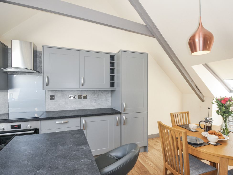 A kitchen with cabinets and dining table at Beach Retreat in Looe