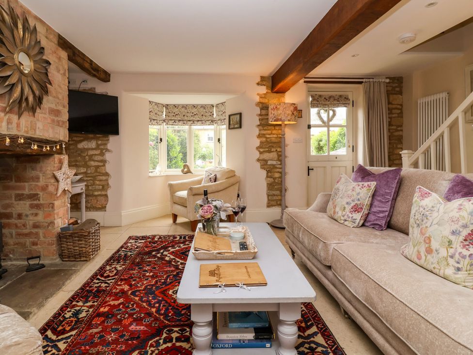 A living room with a sofa, coffee table, and fireplace at Puffitts Cottage in Bourton-on-the-Water