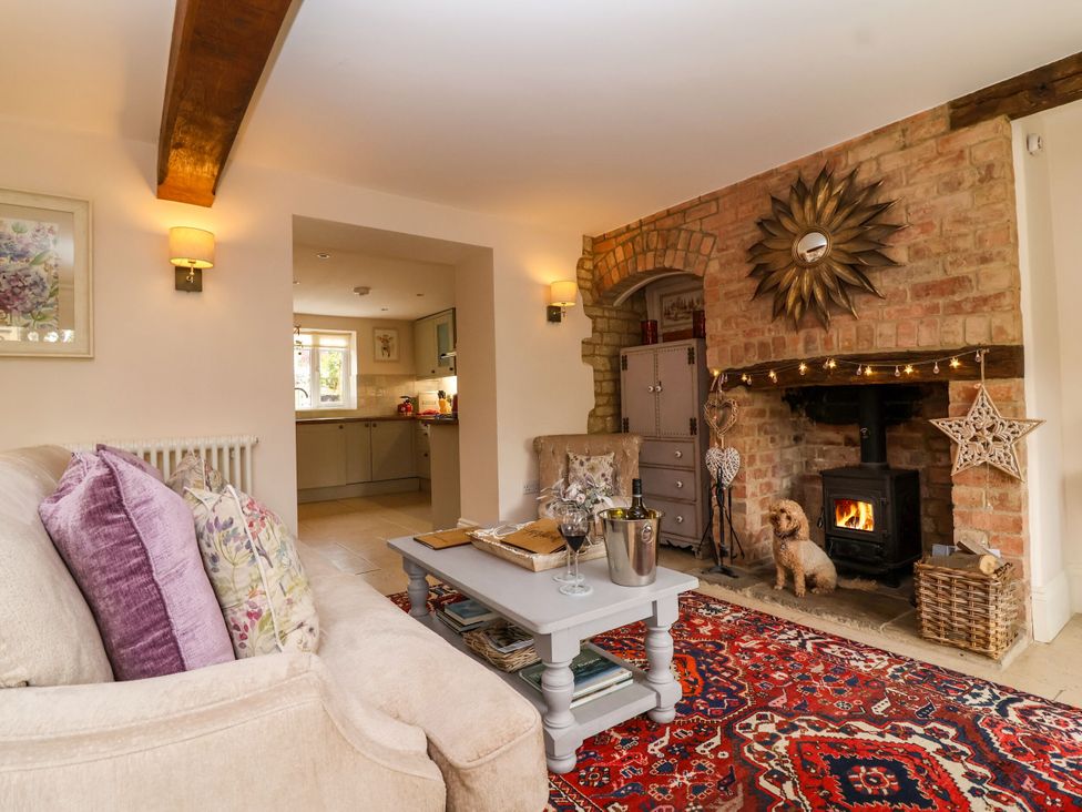 A living room with a fireplace and a dog at Puffitts Cottage Bourton-on-the-Water
