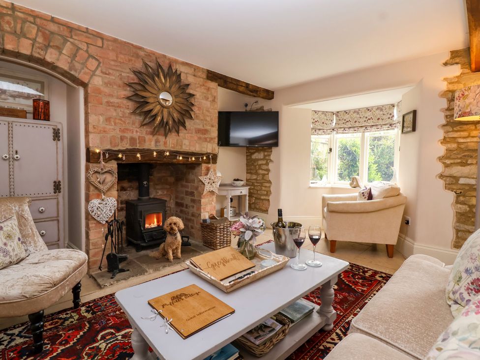 A living room with a wood stove and a coffee table at Puffitts Cottage in Bourton-on-the-Water