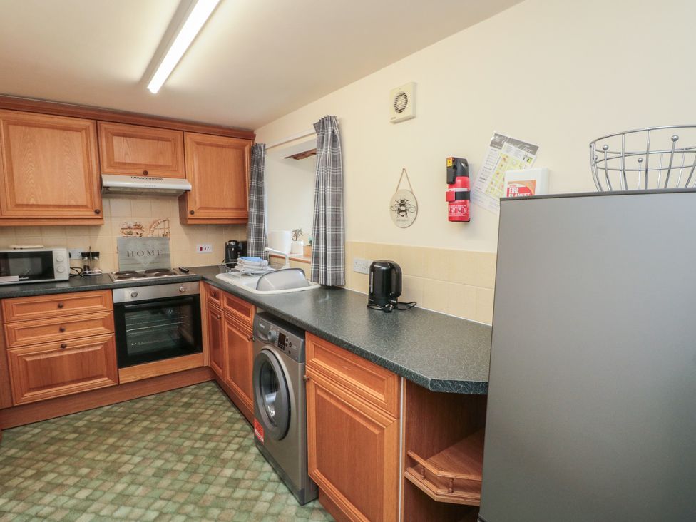 A kitchen with wooden cabinets and appliances at Milton Cottage in Hawsker near Whitby and Robin Hood's Bay