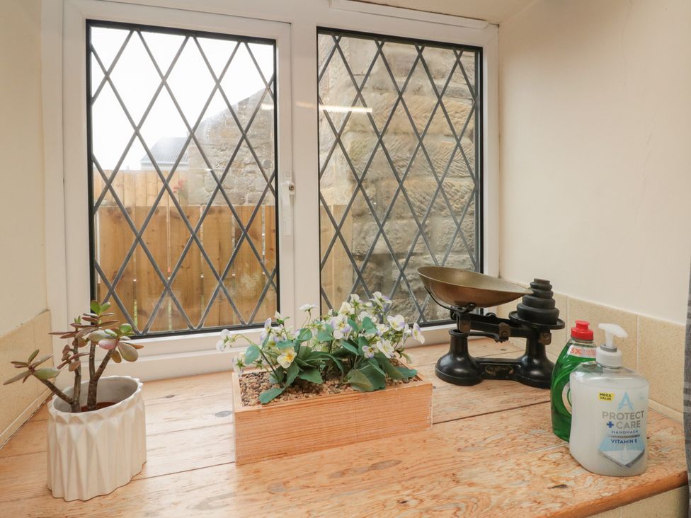 A kitchen window with plants and cleaning supplies at Milton Cottage in Hawsker near Whitby and Robin Hood's Bay