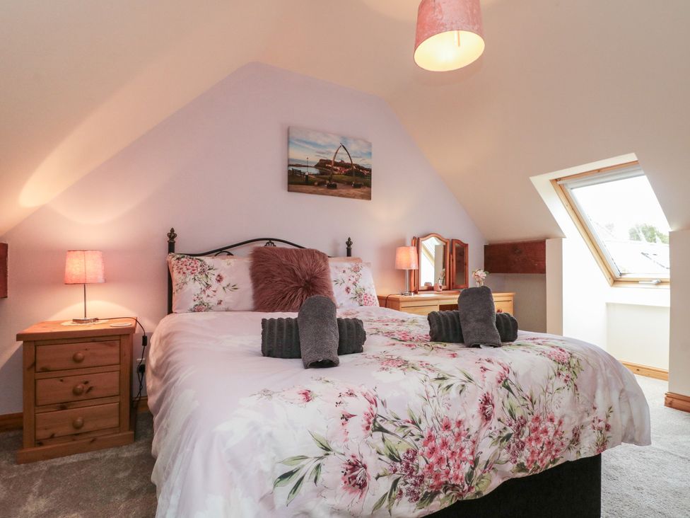 A bedroom with a bed, nightstand, lamp, mirror and window at Milton Cottage in Hawsker near Whitby and Robin Hood's Bay