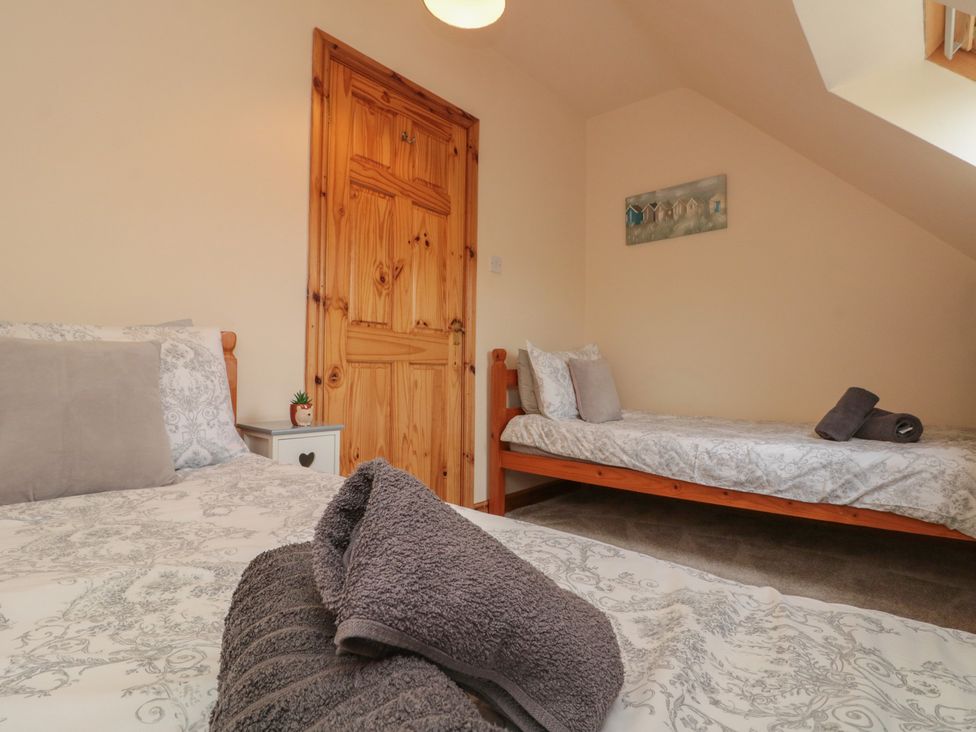 A bedroom with two beds and a wooden door at Milton Cottage in Hawsker near Whitby and Robin Hood's Bay