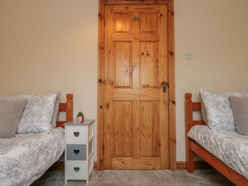A bedroom with two beds and a nightstand at Milton Cottage in Hawsker near Whitby and Robin Hood's Bay