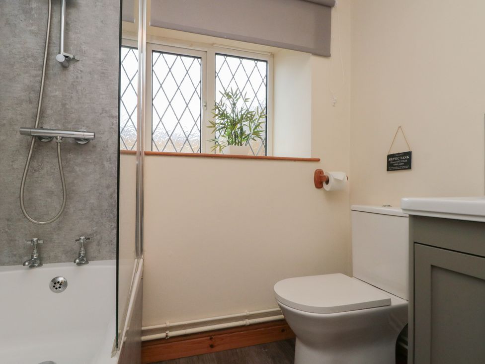 A bathroom with a shower, bathtub, toilet, and window at Milton Cottage in Hawsker near Whitby and Robin Hood's Bay