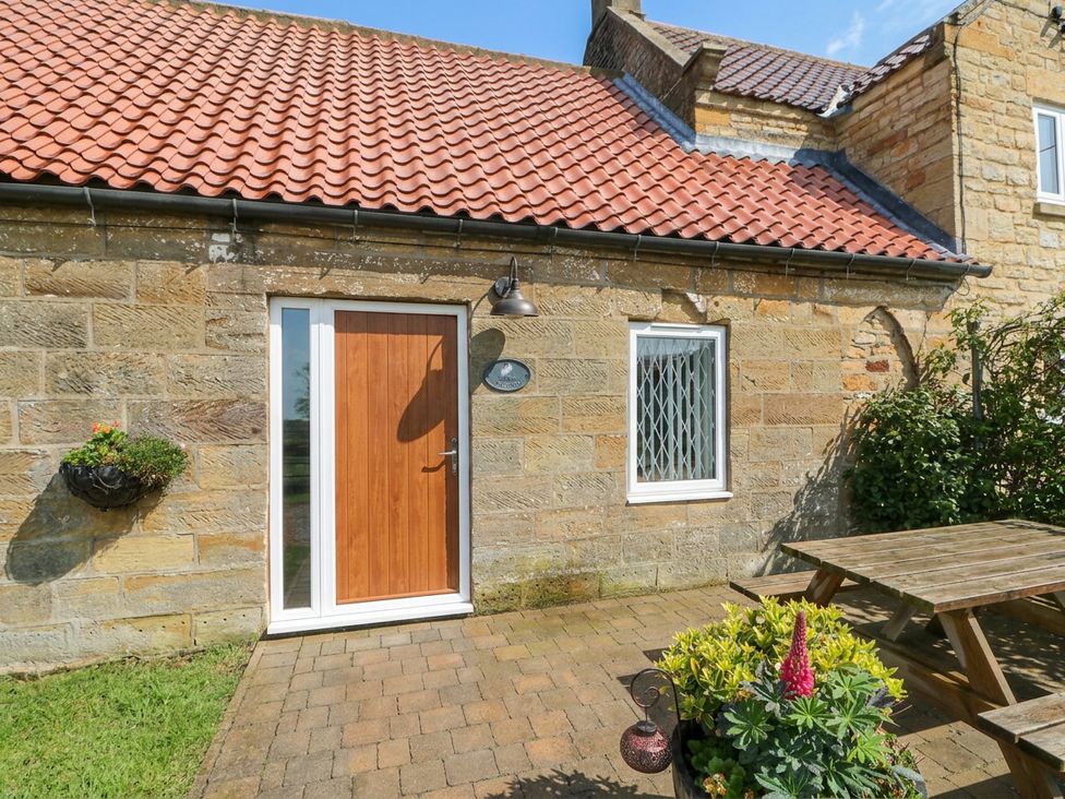 An outdoor area with a wooden door and flower pot at Milton Cottage in Hawsker near Whitby and Robin Hood's Bay
