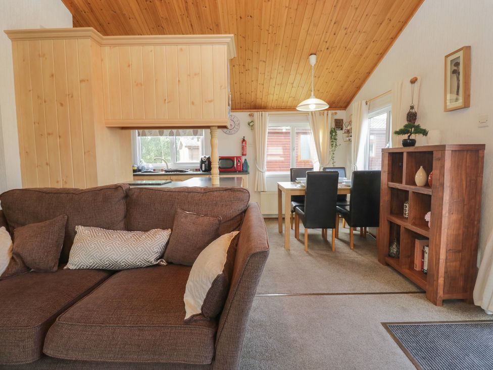 A living room with a sofa and dining area at The Cedars in South Lakeland Leisure Village