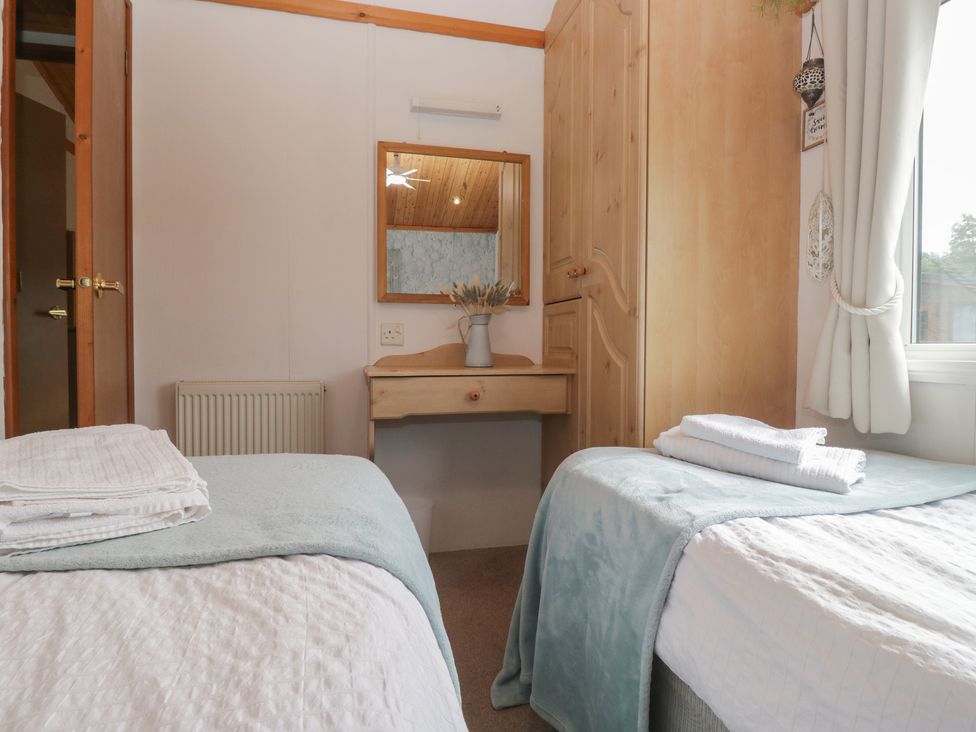 A bedroom with two beds and a mirror at The Cedars South Lakeland Leisure Village