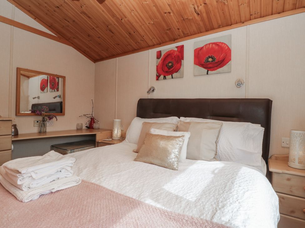 A bedroom with a bed and a mirror at The Cedars in South Lakeland Leisure Village