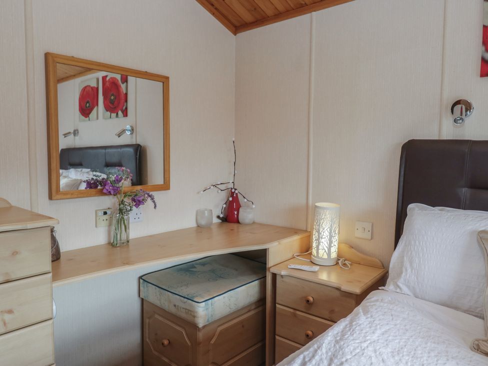 A bedroom with a mirror and a bed at The Cedars, South Lakeland Leisure Village
