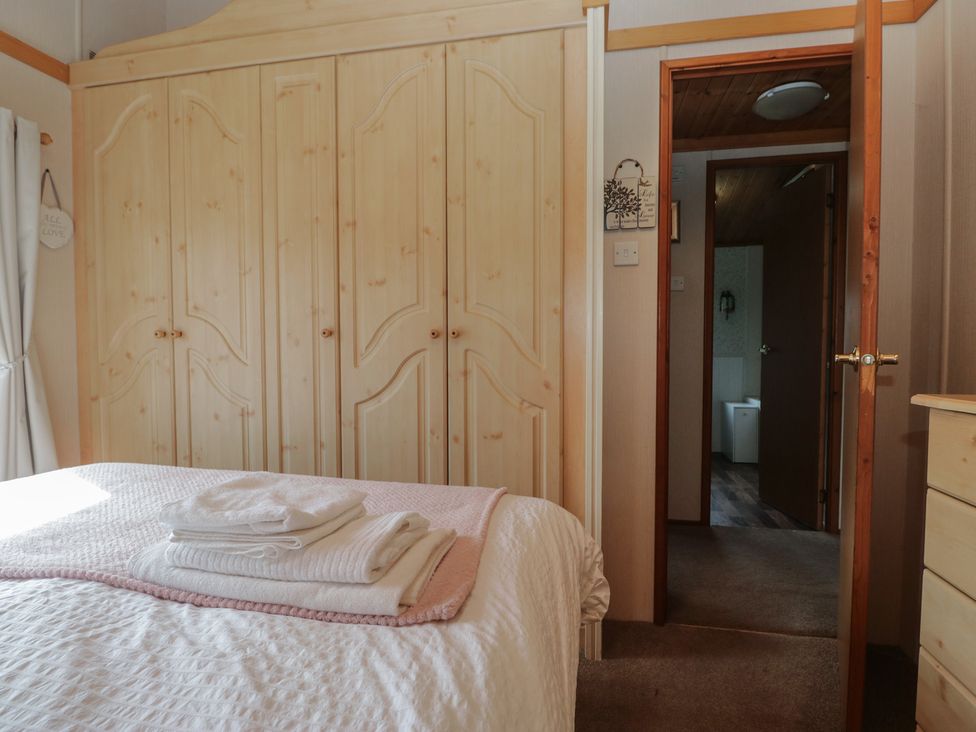 A bedroom with a bed and wardrobe at The Cedars in South Lakeland Leisure Village