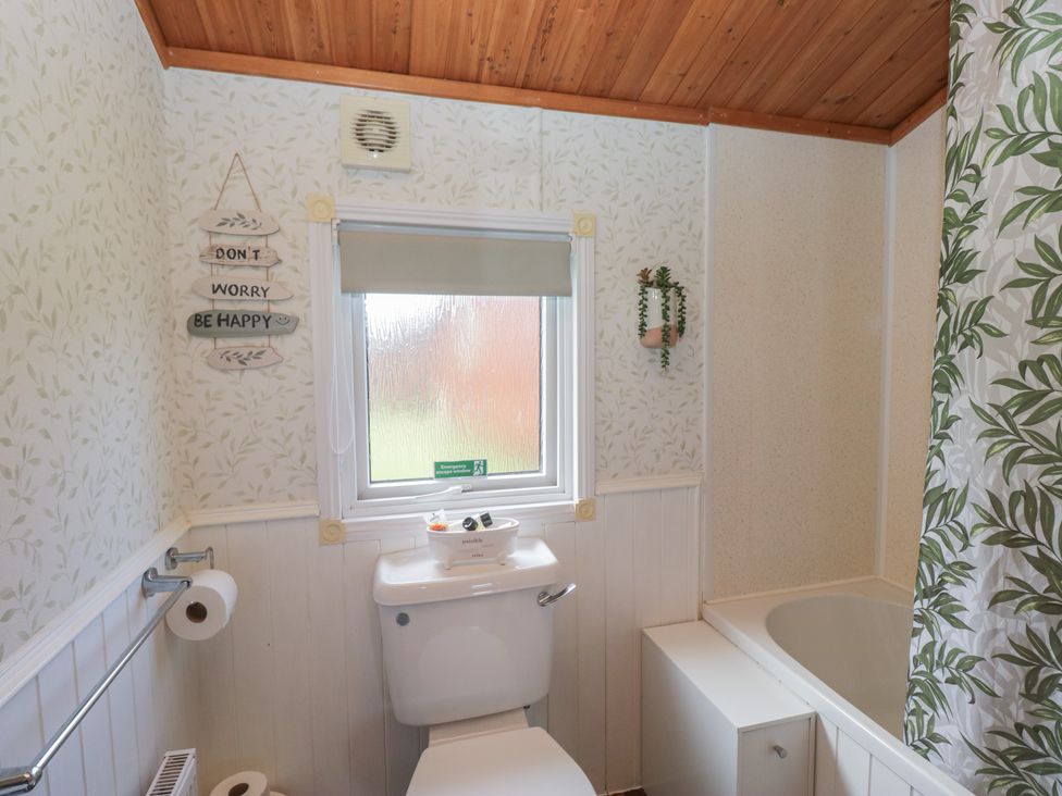 A bathroom with a toilet and bathtub at The Cedars in South Lakeland Leisure Village