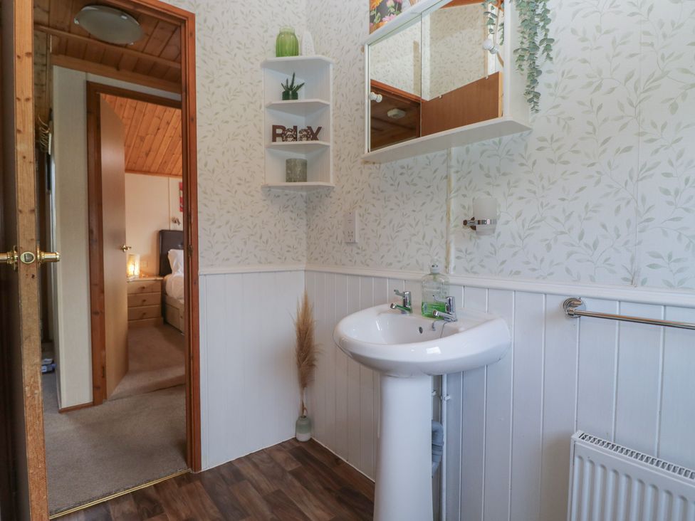 A bathroom with a sink and mirror at The Cedars in South Lakeland Leisure Village