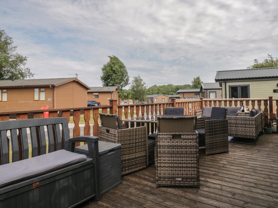 A deck with outdoor chairs and table at The Cedars in South Lakeland Leisure Village
