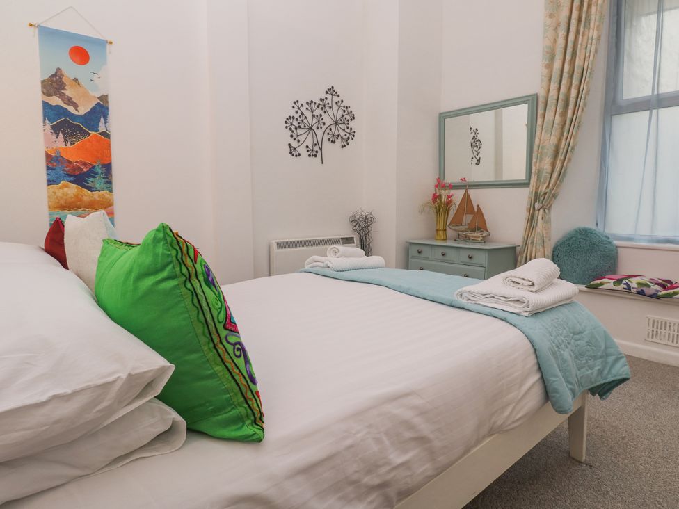 A bedroom with a bed, mirror, and decorative items at Beachcomber in Marazion