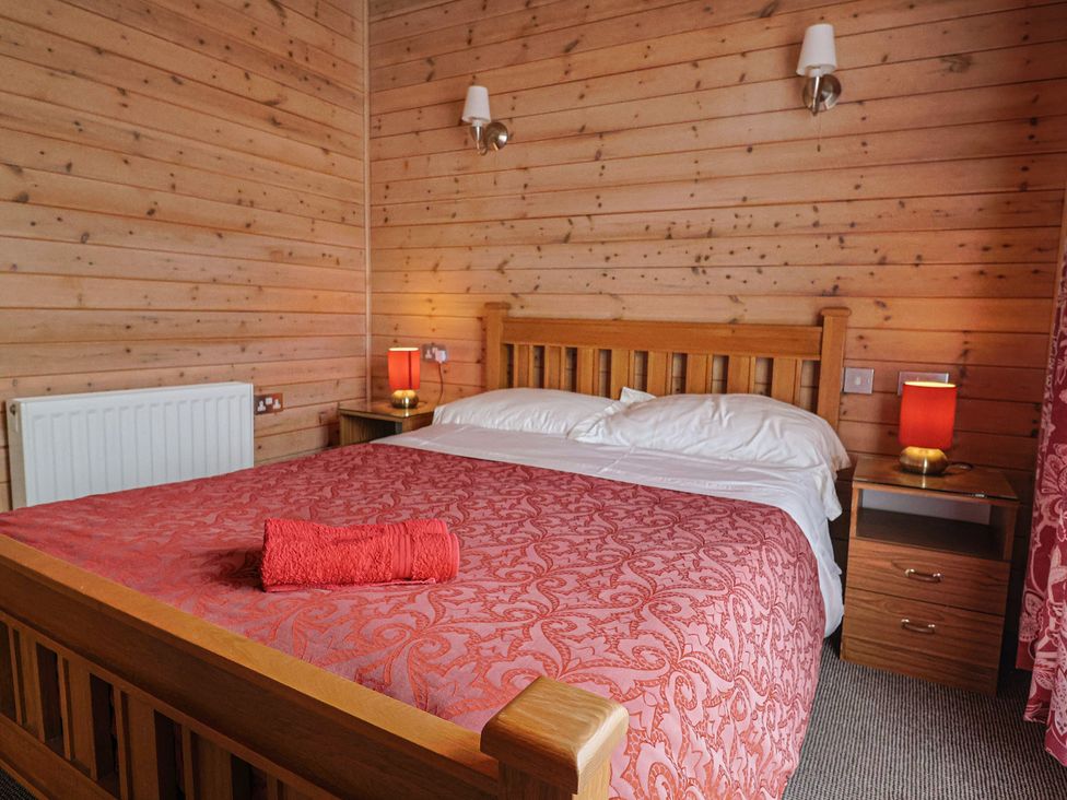 A bedroom with a wooden bed and bedside tables at The Cabin at East Hill Pride Four Elms Hill Nr. Sidmouth
