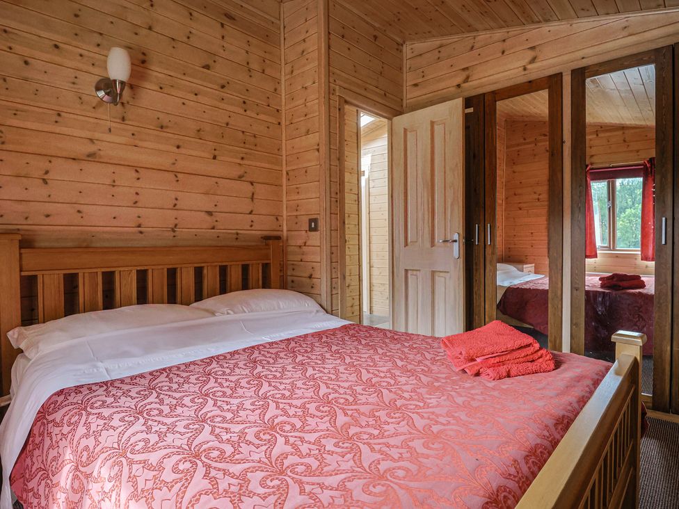 A bedroom with a double bed and wooden furniture at The Cabin at East Hill Pride Four Elms Hill Nr. Sidmouth