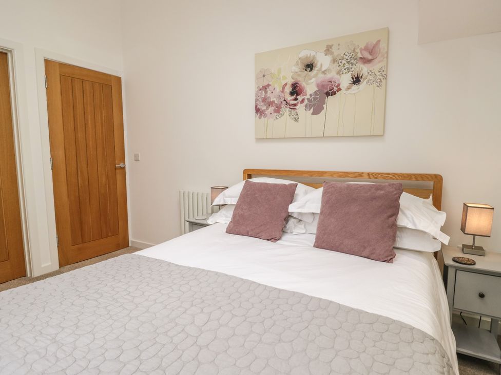 A bedroom with a bed and a painting at Coney Garth Barn in Beckermet