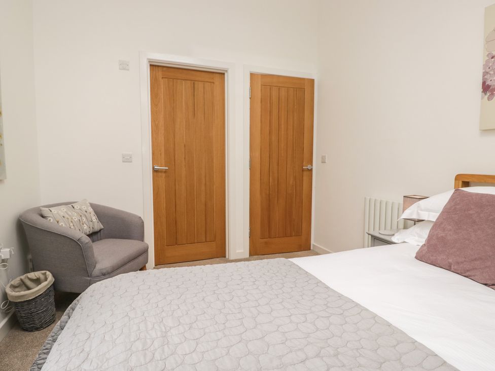 A bedroom with two doors and a chair at Coney Garth Barn in Beckermet