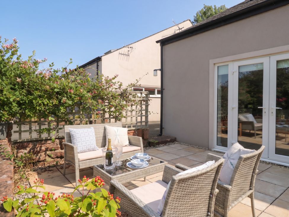 An outdoor seating area with a table and wine at Coney Garth Barn Beckermet