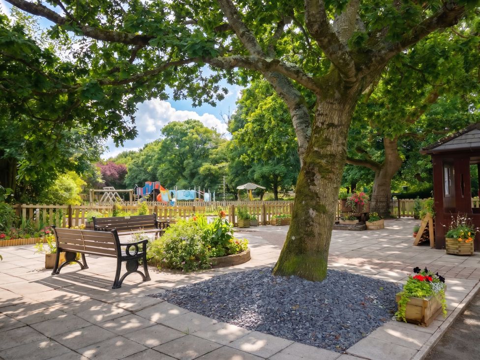 A garden with benches, a playground and flowerbeds at Coney Garth Barn in Beckermet