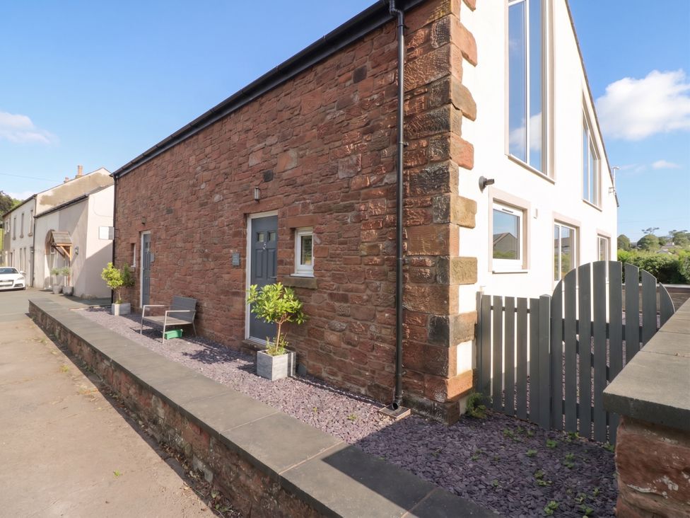 An outdoor area with a stone wall and bench at Coney Garth Retreat in Beckermet