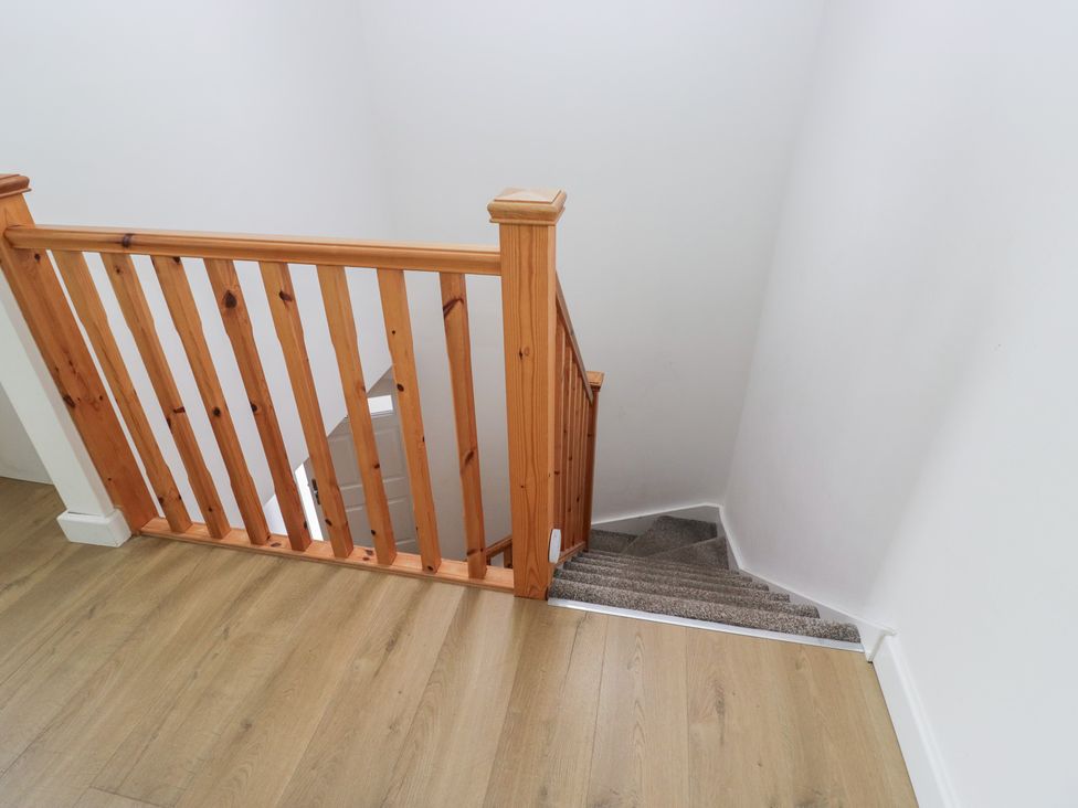A staircase with wooden handrail at Coney Garth Retreat in Beckermet
