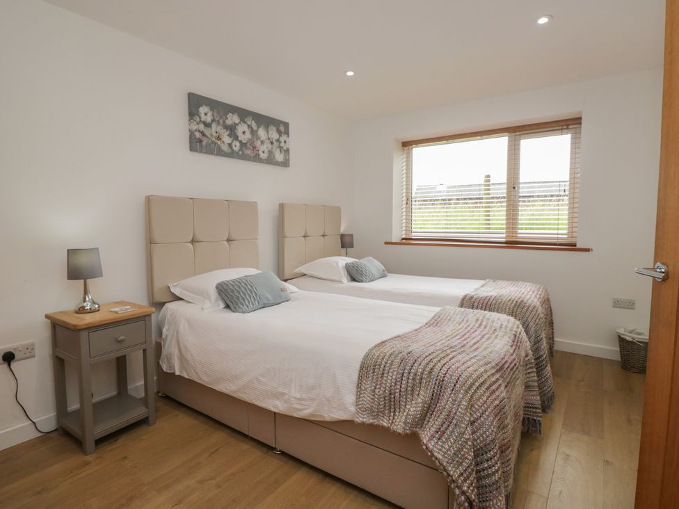 A bedroom with two beds and a bedside table at Coney Garth Retreat in Beckermet