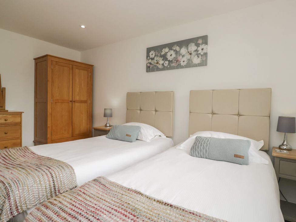 A bedroom with twin beds and a wardrobe at Coney Garth Retreat in Beckermet