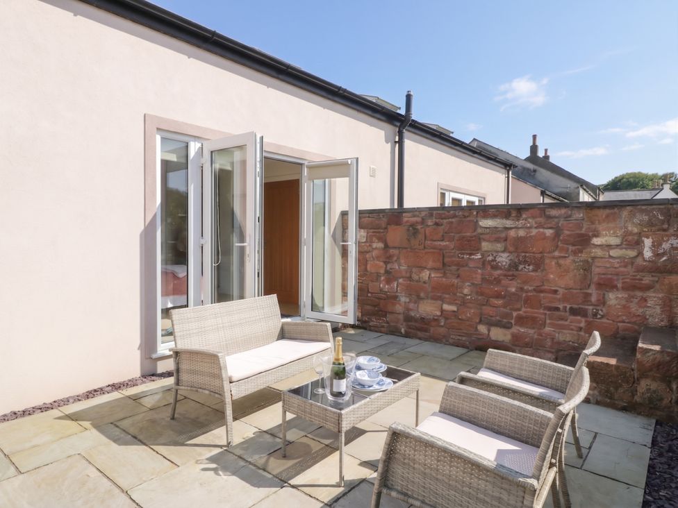 A patio with chairs and a table at Coney Garth Retreat in Beckermet
